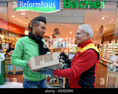Braunschweig, Deutschland. 21. Dezember 2016. Paket-Zusteller Hans-Joachim Harnagel liefert ein Paket an Holger Mus (l) Besitzer von einem Bioladen während einer Lieferung Runde in Braunschweig, Deutschland, 21. Dezember 2016. Rund 280 Päckchen und Pakete liefern wir an ihre Empfänger während einer Reise durch die Innenstadt von Braunschweig. Foto: Holger Hollemann/Dpa/Alamy Live News Stockfoto