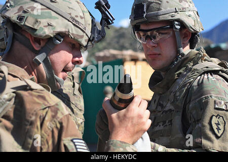 US Armee Sgt. John Henington, links, aus Alpha-Batterie, 3. Brigade, 7. Feldartillerie, 25 Infanterie-Division, inspiziert eine 105 mm Artillerie rund, während Bronco über Watch Betrieb bei Combat Outpost Monti im Shaw-Tal, Asmar District, Provinz Kunar, Afghanistan, 14. Oktober 2011. Betrieb Bogen ermöglicht TF Monti, 3rd Brigade Combat Team, 25. Infanterie-Division, Task Force Bronco, richten Sie ein über ein beobachten Sie Position und zur Gewährleistung der Freiheit der Versorgung Bewegungen durchlaufen California route. Bogen-Betrieb 111014-A-RR514-865 Stockfoto