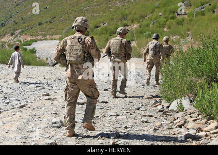 US-Soldaten mit Pfadfinderzug, 2. Bataillon, 27. Infanterieregiment, 3. Brigade Combat Team, 25. Infanteriedivision folgen einem afghanischen Jungen, der während der Operation Bronco Over Watch in der Provinz Kunar, Afghanistan, einen Sprengdraht entdeckt hat, um die Versorgungswege zu schützen. Stockfoto
