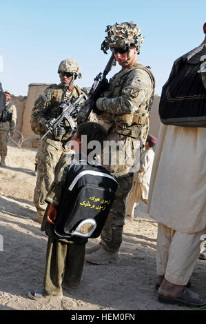 US Armee Sgt. Jason Lambright, der schützenden Service Detail 3rd Brigade Combat Team, 10th Mountain Division und Staff Sgt Byron C. Ryce, persönliche Sicherheitsoffizier, der stellvertretender Kommandierender general des Supports, Hauptsitz und zentrale Battalion, 82. US-Luftlandedivision, stehen in der Nähe ein afghanischer Junge wartet auf seinem Heimweg nach dem Besuch der offenen Tür an einer Schule außerhalb der Forward Operating Base Howz-e-Madad in Kandahar , Afghanistan, 16. November 2011. Der junge Schule statt ein offenes Haus, und er war angesichts der Tatsache, dass Rucksack mit Schulmaterial gefüllt. (US Armee-Foto von Sgt. Amanda Hils/freigegeben Stockfoto