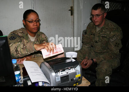 KANDAHAR, Afghanistan – Staff Sgt Stephanie Hawkins, Finanzen Unteroffizier im Laden mit 33. Financial Management Company, 7. Sustainment Brigade Währung Afghani in eine Geldmaschine unter der Beobachtung der Staff Sgt Philip Wynn, ein NCO mit 10. Kavallerie-Regiment, 2nd Brigade Combat Team, 1. Staffel, 4. US-Infanteriedivision, Jan. 18 ernährt. Wynn ist Geld ausgegeben, um afghanische Bauunternehmen Bauarbeiten am Lager Nathan Smith zu tun zu bezahlen.  (US Armee-Foto von Sgt. Ruth Pagan, 2nd Brigade Combat Team, 4. US-Infanteriedivision, PAO) Fütterung Maschine 120118-A-VX278-004 Stockfoto