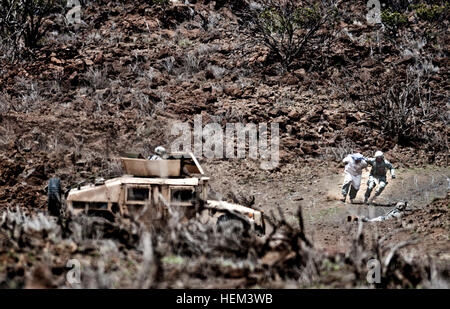 Ein Soldat zugewiesen 558th Military Police Company, 728th MP-Bataillon, 8. MP-Brigade von Schofield Barracks, Hawaii, eilt ein lokaler nationaler Sicherheit als feindliche Kombattanten Angriff einen temporären Checkpoint während des Unternehmens 558th MP Bereich trainieren Sie im Pohakuloa Trainingsbereich, Hawaii, 24. März 2012. Die Einheit durchgeführt Team Ebene Schlacht Bohrer, taktische Kenntnisse der Einheit zu trainieren. Big Island Military Police Training März 23-24 120324-A-TW035-001 Stockfoto