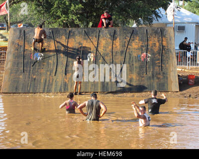 Spartan Race Konkurrenten lassen einen Hindernis-Parcours zu einem Spaziergang durch schlammiges Wasser am 19. Mai 2012 in Burnet, Texas über eine Mauer zu klettern.  Die erste Meile war gerade laufen Hügel hinauf und felsigen Pflaster. Modenr Krieger teilnehmen in Spartan Race 120519-A-UN001-003 Stockfoto