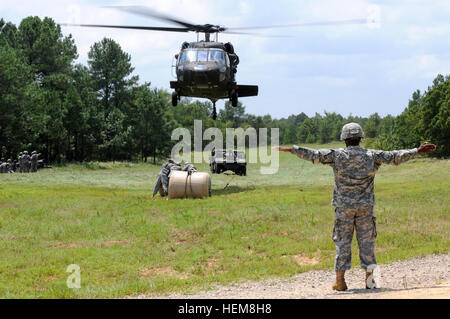 Sgt. Brucious Pigott gibt Hand- und Armbewegungen Signale auf einem UH-60 Black Hawk, sodass Fallschirmjäger sicher eine Schlinge geladen Wasser Blivet an der Unterseite des Flugzeuges anbringen können. Fallschirmjäger zugewiesen 407th Brigade Support Battalion, 2nd Brigade Combat Team, 82nd Airborne Division, zusammen mit Mitgliedern der North Carolina National Guard Schlinge führen laden Training mit der Drehflügler, 31.Juli. Während diese Fallschirmjäger ständig trainieren, um am Schlinge Ladevorgänge beherrschen, war diese Übung eine Gelegenheit für die Support-Spezialisten, die Last auf den Hubschrauber als es eigentlich Haken Stockfoto