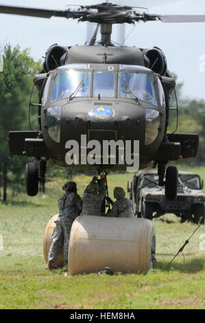 Fallschirmjäger Haken eine Schlinge geladen Wasser Blivet an der Unterseite des UH-60 Black Hawk im Tragetuch Last training, 31.Juli. Fallschirmjäger zugewiesen 407th Brigade Support Battalion, 2nd Brigade Combat Team, 82nd Airborne Division, eine Partnerschaft mit Mitgliedern der North Carolina National Guard, die Ausbildung mit der Drehflügler durchzuführen. Während diese Fallschirmjäger ständig trainieren, um am Schlinge Ladevorgänge beherrschen, war diese Übung eine Gelegenheit für die Support-Spezialisten, tatsächlich die Last an der Unterseite des Hubschraubers Haken, da es nur Füße über ihren Köpfen schwebt. Schlinge Stockfoto