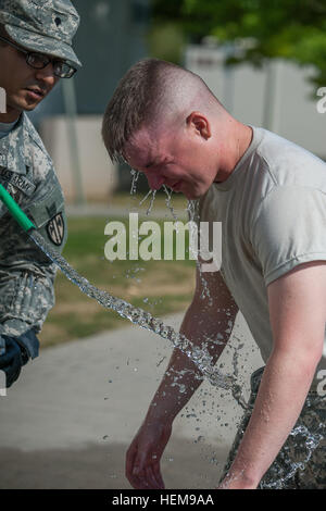 Eine Militärpolizei von 554 Military Police Company leiden die Auswirkungen von Oleoresin Capsicum, OC-Spray verwendet einen Wasserschlauch, waschen die Kontamination von nach wenigen Ebene eine Kontamination in denen die Soldaten gesprüht werden mit Oleoresin Capsicum, OC spray in ihrem Gesicht, welche Ursachen Reizung der Haut, geschwollene Augen und Atemnot. Der Soldat muss dann Aufgaben einschließlich Streiks Ellbogen, Knie Streiks und defensive Bewegungen unter dem Einfluss der OC-Spray. (US Armee-Foto von Martin Greeson) (Freigegeben) Kontamination, die Ausbildung 120823-A-YI962-261 Stockfoto