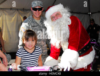 PFC. Jefferey Crawford mit dem 2-285. Aviation Bataillon der Arizona National Guard hilft ein neues Fahrrad, ein Kind mit Hilfe von Santa Claus, während "Fahrräder für Kinder" in Phoenix, Dez. 8 verteilen. Die Guard-Mitglieder Anzeige einem Blackhawk-Hubschrauber und ein paar Armee LKW vorgesehenen sowie half die Überraschung der Fahrrad Geschenke an die Kinder und sie austeilen zu präsentieren. Neben Phoenix Polizei und Feuerwehr haben dabei geholfen, die Guard-Mitglieder auf einen unvergesslichen Urlaubsereignis für weniger glücklichen Familien in der Gemeinde. Ein neues Fahrrad 121208-A-TA765-137 Stockfoto