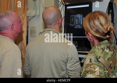 Mitglieder des Lagman vorwärts Chirurgenteams diskutieren Mohammed Qasims x-ray auf Forward Operating Base Lagman, Afghanistan, am 13. Dezember 2012.  Mohammed Qasim, ein Afghane uniformierten Polizisten mit der 4. Firma Reserve Kandak, wurde zwei Monate zuvor durch einen improvisierten Sprengsatz verletzt und wurde von den Hawaii National Guard Sicherheit Kräfte Advisory Team 21, die Partner mit Qasim Einheit Lagman vorwärts Chirurgenteams gebracht.  (US Armee-Foto von Sgt. Lori Bilyou) Afghanischer Polizist geholfen durch SFAT, FST 121213-A-BF245-431 Stockfoto