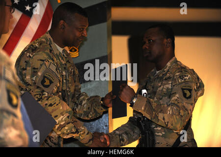 US Armee Sgt. Clement Adu, ALSE Techniker, D Company, 6. Bataillon, 101st Combat Aviation Brigade, 101st Airborne Division (Air Assault), erhält einen Ordner mit den Eid der Induktion, das Credo der Unteroffizier und NCO Führer von Command Sergeant Major Alonzo Smith, senior verpflichtete Berater, Combined Joint Task Force-101, 101. Abn. Div. während der NCO Induktion Zeremonie in der Grady Esszimmer Einrichtung, 31. März 2013. Der Zweck der Zeremonie wurde offiziell die neue NCO in die Reihen des NCO Korps willkommen. (US Armee-Foto von Staff Sgt Jerry Saslav, 129. Mobil Stockfoto