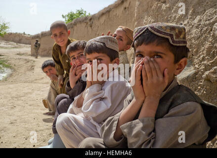 Kinder sehen US-Soldaten zugewiesen Alpha Company, 2. Bataillon, 4. Stryker Brigade Combat Team, 23. Infanterie-Regiment 2. Infanterie-Division, als sie bieten Sicherheit für Mitglieder der afghanischen Nationalarmee 4. Kandak, 205. Korps bei Betrieb Blackhawk Talon, auf eine afghanische Armee führte Suche nach Waffe und explosive Caches in einem Dorf von Zabul Provinz zugewiesen , Afghanistan, 25. April 2013. Betrieb Blackhawk Talon aufgenommen Soldaten mit der 2. Eskadron, 1. Kavallerie-Regiment, 1st Armored Brigade Combat Team, kombiniert Task Force Raider, 3. Infanterie-Division, eine Stockfoto