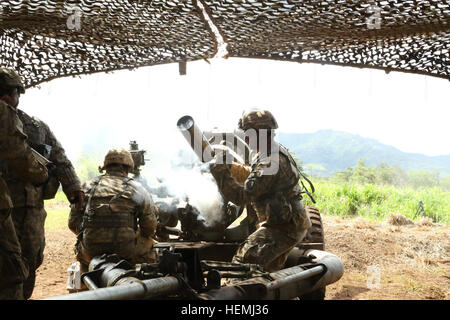 SPC. Roy Alcoran Uhren durch die Sehenswürdigkeiten während Spc. Kyle Gonzales, 25. Infanterie-Division Alpha Batterie, 3. Bataillon, 7. Feldartillerie, 3rd Brigade Combat Team zugewiesen ist, wirft ein Stück heißen Messing aus dem Weg zur Unterstützung der Operation Bronco Rumble, Mai 7, hier bei feuern Punkt 101. Bronco Rumble ist eine kombinierte Waffen Feuer Übung durchgeführt Mai 1 bis 14, Führer und Service-Mitglieder mit kritischem Denken und taktisches Geschick zu entwickeln, während die übrigen bereit, die Armee Mission im pazifischen Raum zu unterstützen. Bronco Rumble wird künftige Interoperabilität mit unseren Paci erhöhen. Stockfoto