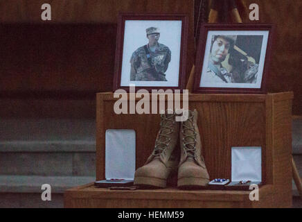 Gerahmte Fotografien erscheinen neben dem Schlachtfeld Kreuz verwendet für eine Gedenkfeier für die US Army Spc. Hilda Clayton auf Forward Operating Base Gamberi, Afghanistan, 8. Juli 2013 statt. SPC. Clayton starb beim Fotografieren der Afghan National Army Soldaten, wie sie eine live-Feuer-Übung 2. Juli 2013 durchgeführt. Eine Mörtel Waffensystem ist fehlgeschlagen, wodurch eine katastrophale Explosion während des Vorfalls vier ANA Soldaten, die Teilnahme an der Schulung starb. Clayton, von Augusta, Georgia, wurde vorwärts in Afghanistan eingesetzt, als die Bekämpfung Kamera-Anlage für die 4th Brigade Combat Team, 1 Stockfoto