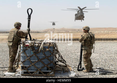 US Army Spc. Robert Ivey, links, und Spc. Gusten Hammond, beide motor Verkehrsunternehmen mit Alpha Company, 703rd Brigade Support Battalion, 4th Infantry Brigade Combat Team, 3. Infanterie-Division, bereiten Sie sich Last Transportausrüstung, ein CH-47 Chinook-Hubschrauber in der Provinz Logar, Afghanistan, 15. Juli 2013 auf Forward Operating Base Schaft Schlinge. Soldaten Operationen routinemäßig Schlinge Last für den transport von Baumaschinen und Zubehör in Afghanistan.  (US Armee-Foto von Sgt. Sarah Bailey/freigegeben) Avantgarden Schlinge laden Ausrüstung, Chinook-Hubschrauber in Afghanistan 130715-A-FN421-001 Stockfoto