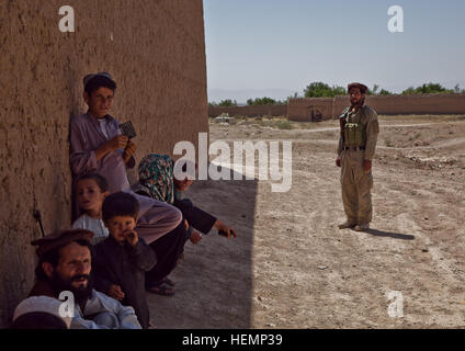 Eine afghanische Polizei steht Wache, während Einheimische warten an einem medizinischen Seminar im Bezirk Deh Yak, Provinz Ghazni, Afghanistan, 19. August 2013. Fünfzig Männer, Frauen und Kinder aus Pajak Dorf und Umgebung besucht das medizinische Seminar, das Themen wie erste Hilfe, Hygiene, Notfall Geburt Techniken und Ernährung.  (US Armee-Foto von Spc. Jessica Reyna DeBooy/freigegeben) Enduring Freedom 130820-A-SL739-013 Stockfoto