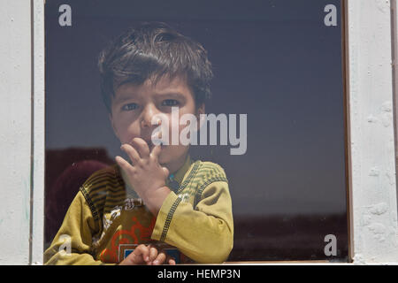 Afghanischer Junge steht im Fenster während eines medizinischen Seminar im Bezirk Deh Yak, Provinz Ghazni, Afghanistan, 19. August 2013. Fünfzig Männer, Frauen und Kinder aus Pajak Dorf und Umgebung besucht das medizinische Seminar, das Themen wie erste Hilfe, Hygiene, Notfall Geburt Techniken und Ernährung.  (US Armee-Foto von Spc. Jessica Reyna DeBooy/freigegeben) Enduring Freedom 130820-A-SL739-045 Stockfoto