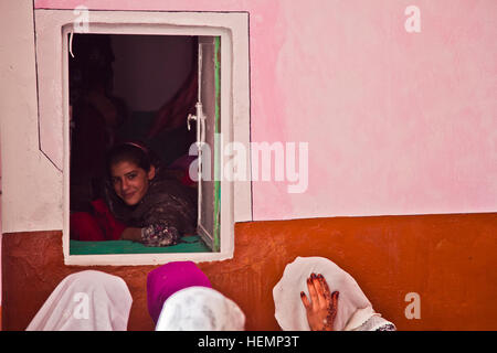 Eine junge afghanische Frau sitzt in einem Fenster beim Hören eines Vortrags zum Thema Notfall Geburt während eines medizinischen Seminars im Bezirk Deh Yak, Provinz Ghazni, Afghanistan, 19. August 2013. Fünfzig Männer, Frauen und Kinder aus Pajak Dorf und Umgebung besucht das medizinische Seminar, das Themen wie erste Hilfe, Hygiene, Notfall Geburt Techniken und Ernährung.  (US Armee-Foto von Spc. Jessica Reyna DeBooy/freigegeben) Enduring Freedom 130820-A-SL739-048 Stockfoto