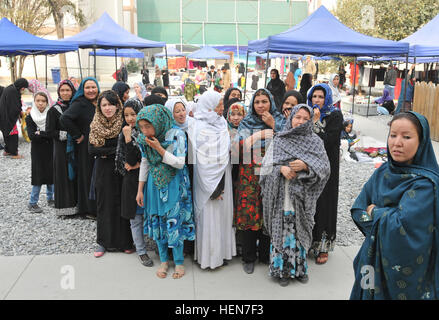 Spät Teenager durch ältere afghanische Somen sind aufgereiht und warten auf die Kinder zu beenden, die Geschenk-Stationen durchlaufen, bevor sie dürfen ihre Gelegenheit, bei den afghanischen Frauen Basar, neue Compound Kabul, Afghanistan, am 23. Oktober 2013. Die afghanischen Frauen und Kinder ans NKC zu Hause gesponnen Kunsthandwerk verkaufen, und der Basar ist eine Chance für die Frauen und Kinder zur Unterstützung ihrer Familien durch den Verkauf von afghanischen Souvenirs. (Fotos: US-Armee Sgt. 1. Klasse Timothy Rasen, 1. Theater Sustainment Command Public Affairs/freigegeben) Chitter-Geschwätz von kleinen Kindern füllen die Stockfoto