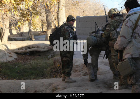 Ein Kommando der Afghan National Army (ANA), 2. Kompanie, 3. spezielle Operationen Kandak (SOK) beobachtet, wie ein US-Explosive Ordnance Ablösung Soldaten eine alte Artillerie-Hülle gefunden bei der Abfertigung von Perozi Dorf, Panjwai District, Provinz Kandahar, Afghanistan, 4. Dezember 2013 inspiziert. 3. SOK mit Unterstützung von uns Soldaten führte die Clearance um Aufständischen Kontrolle zu stören und weitere improvisierten Sprengkörpern Einlagerung und Kleinwaffen Angriffe zu verhindern.  (Foto: US Army Staff Sgt Bertha A. Flores / veröffentlicht) Perozi Räumungsarbeiten 131204-A-LW390-097 Stockfoto