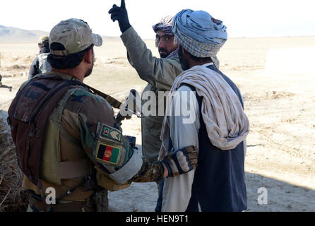 Ein Soldat der Afghan National Army Special Forces (links) und ein afghanischer Polizist (Mitte) fordern einen Dorfbewohner über den Standort von Taliban Mitglieder Häuser während einer Clearing-Operation in Mohammad Ghaws Dorf Waffenlager 16. Dezember 2013, im Ab Band District, Provinz Ghazni, Afghanistan. Die Sicherheitskräfte entdeckten viele improvisierte explosive Vorrichtungen und Waffen Caches während des Betriebs. Sie fanden mehrere Pfund hausgemachte Sprengstoff, Handgranaten, ca. 200 Schuss von AK-47 Angriff Gewehrmunition und medizinische Versorgung. (Foto: US-Armee Sgt. Jared Gehmann) ANASF, ALP reduzieren Waffe Stockfoto