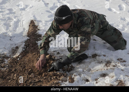 Ein Mitglied der afghanischen Nationalarmee mit der 8. Sondereinsätze Kandak identifiziert während des letzten praktischen Tests des Kurses zur Reduzierung der Explosivgefahr im Distrikt Pul-E Alam, Provinz Logar, Afghanistan, 11. Januar 2014 einen potentiellen Ort für improvisierte Sprengkörper. Stockfoto