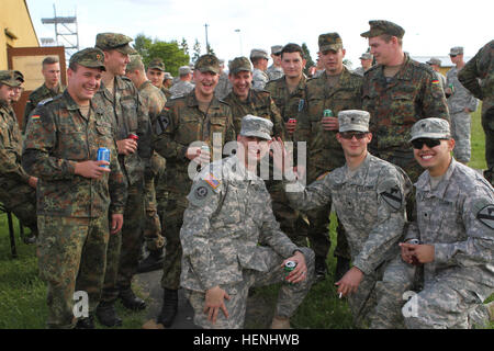 Deutsche Soldaten aus der 4. Kompanie, 467th Logistik-Bataillon und Soldaten aus dem 1. Brigade Combat Team, 1. Kavallerie-Division, Pose für ein Foto in einem Grill nach dem ersten Tag der Schuetzenschnur, ein deutscher Waffen Eignungsprüfung in Grafenwöhr Army-Basis. Soldaten der 1. Brigade Combat Team, 1. Kavallerie-Division und deutsche Soldaten der 4. Kompanie, 467th Logistik-Bataillon, zwei Tage interagieren und die Teilnahme an einem Leistungstest Waffen während der multinationalen Übung lösen II kombiniert. Soldat Interaktion 140605-A-SJ786-012 Stockfoto