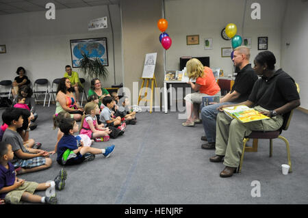 Karen Masley liest ein Buch, "Polare Gegensätze," den Kindern während Oberst Michael E. Masley, Yongsan Garrison Kommandant und Command Sergeant Major Henney M. Hodgkins, Garrison Command Sergeant Major, geduldig warten ihre Schwünge in den Sommer Lesung Programm Kickoff Zeremonie in Yongsan Bibliothek, Juni 14. (US Armee-Foto von Pfc. Moon Hyungju) Sommer-Leseprogramm lädt Area II nach "Paws to Read" 140614-A-MV987-002 Stockfoto