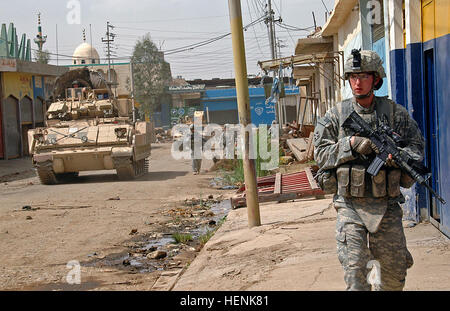 PFC. Adam Devries, eine Infanterie Soldat im 1. Zug, Firma D, 1. Bataillon, 8. Infanterie-Regiment vom Fort Carson, Colorado, Patrouillen der Straßen von Mosul, bewegt sich am 1.April, mit Mitgliedern seines Unternehmens unter als ein Bradley Armored Personnel Carrier an der Seite, die Gewährleistung der Sicherheit. Irakische Armee-Division führte Überfall auf Mosul Nachbarschaft findet Autobombe Fabrik 83278 Stockfoto