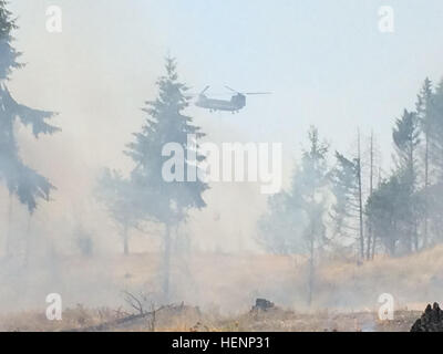 Washington National Guard CH-47 Chinook Helikopter sinkt 2.000 Gallonen Wasser auf einem 350-Acre Wildfire auf Joint Base Lewis-McChord, Wash., 11. August 2014. Laut der JBLM Zweig der forstwirtschaftliche Dienstleistungen ist das Wildfire 90 Prozent enthalten. (Staff SGT Jennifer Spradlin, 19. Public Affairs-Abteilung) Mehrere Agenturen arbeiten, um JBLM Wildfire 140811-A-OP586-394 enthalten Stockfoto