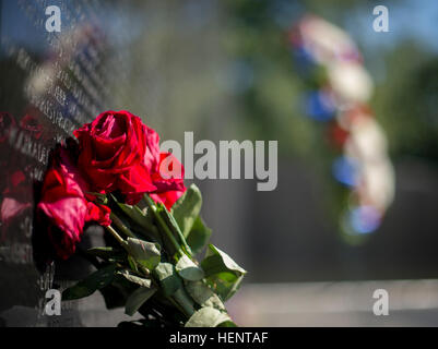 Ein Strauß Rosen, links um den Toten zu gedenken schmückt das Vietnam Veterans Memorial in Washington, D.C., 17. September 2014.  Im Hintergrund ist der Kranz zu Ehren Spc. 4 Donald P. Sloat, die posthum wurde Anfang dieser Woche die Medal Of Honor ausgezeichnet.  Sloat zeichnete sich während seiner Zeit als ein MG-Schütze mit der 1. Infanterie-Regiment, 196. Light Infantry Brigade, Filmschaffender Division, während der Kampfhandlungen gegen einen bewaffneten Feind in der Republik von Vietnam. Am Morgen des 17. Januar 1970 zog Sloat Kader auf einem Hügel in der Datei Anordnung, wenn die Führung Soldat einen Draht befestigt ausgelöst Stockfoto