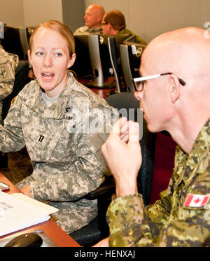 Armee Capt Lauren Nofsinger, Kaplan, sitzt mit kanadischen Armee Generalmajor Harry Crawford, Kaplan, während eine simulierte Zelle Übung an der US Armee Kaplan Center & School in Fort Jackson, S.C. Soldaten beider Nationen verbrachte eine Woche Training als religiöse Berater in verschiedenen Szenarien. US-Armee Kapläne Zug mit einer Kraft aus dem Norden 141021-A-CL830-057 Stockfoto