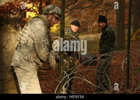 Ein US-Soldat der 91. Brigade-Pionier-Bataillon, 1. Brigade Combat Team, 1. Kavallerie-Division und rumänische Soldaten des 21. Berg Truppen Bataillon, 2. Gebirgsbrigade Truppen, 1st Infantry Division hinzufügen Stacheldraht ein Ziehharmonika-Draht-Hindernis Währenddes Trainings kombiniert zu beheben III bei der Joint Multinational Readiness Center in Hohenfels, Deutschland, 4. November 2014. Kombinierte Lösung III ist eine multinationale Übung, die enthält mehr als 4.000 Teilnehmer aus NATO und Partner, und soll eine komplexe Trainingsszenario bieten dem Schwerpunkt multinationale unified Land wirtschaftli- Stockfoto