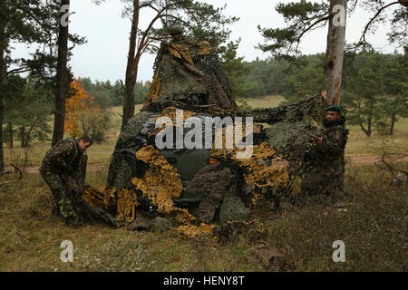 Rumänische Soldaten decken ein Fahrzeug mit Tarnung während des Trainings kombiniert Entschlossenheit III bei der Joint Multinational Readiness Center in Hohenfels, Deutschland, 7. November 2014.  Kombinierte Lösung III ist eine multinationale Übung, die enthält mehr als 4.000 Teilnehmer aus NATO und Partner, und soll eine komplexe Trainingsszenario bieten, die konzentriert sich auf multinationale unified Land Operationen und das US-Engagement für NATO und Europa verstärkt. (US Armee-Foto von Spc. John Kresse Jr./freigegeben) Kombinierte Lösung III 141107-A-AO034-010 Stockfoto