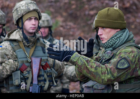 Ein Soldat mit der litauischen Streitkräfte Slips Soldaten aus der ukrainischen Landstreitkräfte 24. November 2015 während der militärischen Grundausbildung im Rahmen der furchtlose Guardian II an der internationalen Friedenssicherung und Security Center in der Nähe von Yavoriv, Ukraine. Die ukrainische Armee werden auf individueller und kollektiver Ebene einschließlich der medizinischen Ausbildung in Bekämpfung Lebensretter und Unfallversicherung Evakuierung Infanterie-basierte, defensiv ausgerichtete geschult. (Foto: US Army Captain Russell M. Gordon, 10. Press Camp Sitz) Furchtlos Guardian II erste Woche der Ausbildung 151124-A-JC015-042 Stockfoto