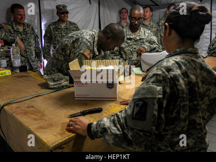 SPC. Guadalupe Shim, Recht, gebürtig aus Dallas und Post-Spezialist für die 18. Human Resources Company, 82. spezielle Truppen Bataillon, 82. Sustainment Brigade unterstützt Spc. Randritz Hopper, zentrieren, gebürtig aus Shelby, NC, und medizinische Logistik-Spezialist für 583rd medizinische Logistik-Unternehmen, 1. medizinische Brigade, mit einem Paket, die er in die USA zurück von Roberts International Airport schickt , Monrovia, Liberia, am 22. Dezember 2014. Das Postamt am Roberts International Airport ist das erste voll funktionsfähige Armee Postamt in Liberia, so dass die Soldaten nach Liberia im Einsatz zu öffnen Stockfoto