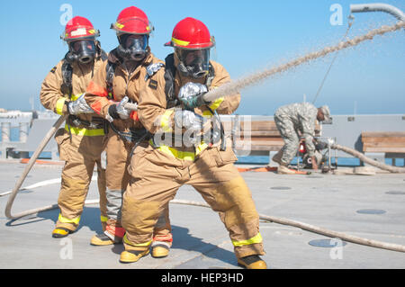 SPC.  Daniel Huntley, von Clayton, Calif., 97. Transportation Company (schwere Boot) zugewiesen, 10. Transport-Bataillon, 7. Transport-Brigade (Expeditionary), steuert die Richtung der Feuerwehrschlauch beim Pfc. Samantha Van Leer, aus Berlin, NJ, und Sgt Douglas Henry aus Strasburg, Pennsylvania, Klammern ihre Teamkollegen während einer simulierten Räumungsübung an Bord der Landing Craft Utility Korinth auf Kuwait Marinestützpunkt , Jan. 24. (US-Armee Fotos von Staff Sgt Gene Arnold, 7. Mobile Public Affairs-Abteilung) Wasserfahrzeuge führt Räumungsübung 150124-A-MX893-003 Stockfoto