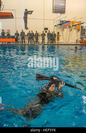 Clemson Universität Reserve Officer Training Corps Kadett Sara Febbo, ein Neuling aus Honolulu, Studium der Biologie, schwimmt mit einem Nachbau eines M16 Gewehr, während einem anderen Kadett Schritte der fünf-Meter-Sprungbrett mit verbundenen Augen hinter ihr, während die Bekämpfung Wasser Survival Test in die Fike Athletic Center 29. Januar 2015 abseits. Die CWST wertet jedes Kadett Ausdauer im Wasser und ihre Fähigkeit, drei Stationen abgeschlossen, während eine Uniform tragen. Vorbei an den Ereignissen hilft sicherzustellen, dass sie die grundlegenden Wasser überleben notwendigen Fähigkeiten, um Soldaten in einer feindlichen Umwelt führen wo es Wasser. (US Armee-Foto Stockfoto