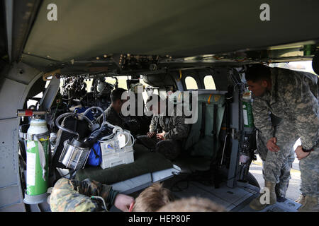 US Army Spc. Christopher Coinbates, rechts, sitzend mit dem 212. Combat Support Hospital, 30. medizinische Brigade erhält Anleitung, wie man richtig einen Sicherheitsgurt im Inneren ein UH-60 Black Hawk Hubschrauber während des multinationalen Medic training im Joint multinational Readiness Center in Hohenfels, Deutschland, 23. März 2015 zu sichern.  Das Ziel dieser Veranstaltung ist für multinationale Soldaten erhalten jährliche Rezertifizierung, erwerben Kenntnisse über die neuen Geräte und Standards und die Interoperabilität zwischen verschiedenen Nationen verbessert.  (US Armee-Foto von Sgt. Gemma Iglesias/freigegeben) Medical training 150323-A-Q Stockfoto