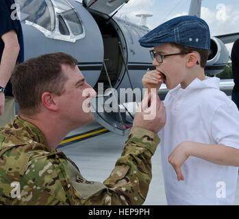 Chief Warrant Officer 4 Jason Boren kniet um das Verwackeln Zahn seines Sohnes Grant, 7, während eine einladende Umschichtung von Familie und Freunden zu inspizieren. US Armee-Reserve-Soldaten C Firma zugeordnete 2nd Battalion, 228th Aviation Regiment zurück von einer achtmonatigen Bereitstellung zu Afghanistan am Papst Army Airfield in Fort Bragg, N.C., 3. April 2015. Die Luftfahrt-Soldaten unterstützt die Bewegung des aufstrebenden Besucher das ganze Theater in c-12 und UC-35-Jets während bereitgestellt. Die Mission diente als das letzte Mal diese speziellen Düsen wird zur Unterstützung der USAR Kampfhandlungen verwendet werden. (US-Armee Stockfoto