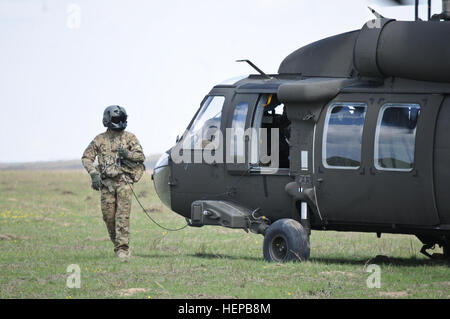 Ein Luft-Crew-Mitglied zugeordnet 4-3 Assault Helicopter Battalion, bereitet einen UH-60 Black Hawk Hubschrauber Luftbrücke britische Soldaten der Coldstream Guard nach tätlichen Angriffs auf ihr Ziel, während Teilnahme an einer Demonstration multinationale kombinierte Waffen neben Soldaten 2. Geschwader, 2. Kavallerie-Regiment und rumänische Land-Kräfte während einer Übung Wind Frühjahr Distinguished Besucher-Veranstaltung im Smardan Trainingsbereich zugeordnet , Rumänien, 18. April 2015. Der Zweck der Veranstaltung war es, Interoperabilität zwischen den NATO-Verbündeten, wobei auch Mitglieder der rumänischen Gover zeigen Stockfoto