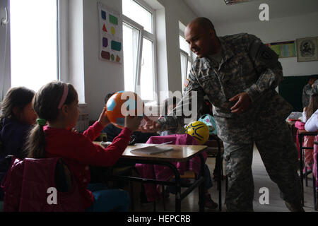 US Armee Sgt. 1. Klasse Kevin Lindquist, eine medizinische Zug-Sergeant für zentrale Headquarters Troop, 1. Staffel (Airborne), 40. Kavallerie-Regiment, 4th Infantry Brigade Combat Team (Airborne), 25. Infanterie-Division und gebürtig aus Queens, New York City, händigt einen Fußball, ein Schüler der Grundschule Vuk Karadjic in Priluzje, Kosovo, 11.Mai besucht. Rund 20 Soldaten aus nach vorne Gefechtsstand und medizinische Task Force mit multinationalen Battle Group-Ost unterrichtete eine Dental-Hygiene-Klasse und Geschenke an die Schüler übergeben. Soldaten bringen Geschenke und Lehren Zahnhygiene, Schüler 1 Stockfoto