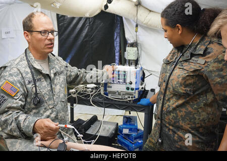 Generalmajor Paul Masters (links), klinische Krankenschwester zuständigen Offizier, Emergency Medical Behandlungsteam, 212. Combat Support Hospital, deutsche Krankenschwester Noelle Franklin (rechts) zeigt den korrekten Gebrauch und verschiedene Einstellungen der Zoll Defibrillator Maschine während der Übung lösen IV kombiniert. 212. CSH und der Bundeswehr haben eine großartige Partnerschaft und cross-training und Integration von zusätzlichem Personal zur Verbesserung der medizinischen Interoperabilität weiter. Ausbildung nebeneinander 150530-A-UA479-904 Stockfoto