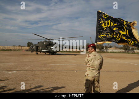 Ein irakischer Soldat zugewiesen Ninive Operations Command Kommando Bataillon zeigt seine Firma, die Farben hinter einer irakischen Mi-17 SH "Black Beauty" im Camp Taji, Irak, 11. Januar 2016 Hubschrauber. Dieses Gebäude Partner Kapazität Training ist entscheidend für die irakischen Sicherheitskräfte Zähler des islamischen Staates im Irak und der Levante ermöglichen, wie sie arbeiten, um das Gebiet von der Terrorgruppe wieder zu erlangen. Das Gebäude Partner Kapazität Mission ist ein integraler Bestandteil der kombiniert Joint Task Force – Betrieb innewohnende lösen multinationalen Bemühungen um Daesh (arabisches Akronym für ISIL) im Irak und Sy militärisch zu besiegen Stockfoto