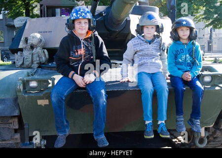 Lettische Bürger Tank Helme tragen und sitzen auf US Army Ausrüstung an eine statische Anzeige zum 25. Jahrestag der lettischen Nationalgarde in Riga, Lettland 20. August 2016. Die Soldaten der 3. kombiniert Arme Bataillon, 69. Armor Regiment, 1st Armored Brigade Combat Team, 3. Infanterie-Division, an der Veranstaltung beteiligt sind Training mit ihren baltischen Verbündeten zur Unterstützung der Operation Atlantic zu lösen, eine US geführten Bemühungen in Ost-Europa, US-Engagement für die kollektive Sicherheit der NATO und das Engagement für dauerhaften Frieden und Stabilität in der Region durchgeführt. 3-69 AR nimmt p Stockfoto