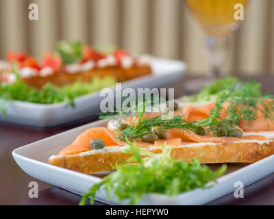 Geräucherter Lachs und Kapern belegte Brötchen mit Glas Bier Stockfoto