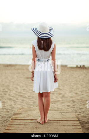 Rückansicht einer Frau auf einen Holzsteg, auf dem Meer suchen Stockfoto