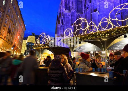 Menschen, die Gluhwein an den Weihnachtsmärkten rund um den Stephansdom, Wien, Österreich trinken, im Dezember Stockfoto