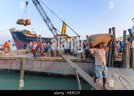 Chittagong: Männer entladen ein Schiff mit Reis in den Hafen von Karnaphuli Fluß, Division Chittagong, Bangladesch Stockfoto