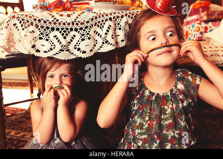 Partygirls Essen süß-saure Süßigkeiten Spaghetti unter dem Tisch Stockfoto