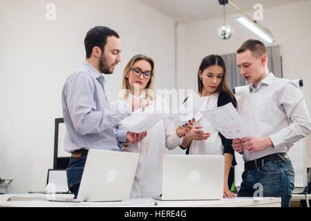 Gruppe von vier verschiedenen Männern und Frauen in Freizeitkleidung im Gespräch im Büro Stockfoto