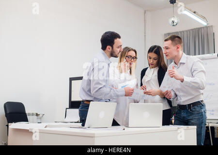 Gruppe von vier verschiedenen Männern und Frauen in Freizeitkleidung im Gespräch im Büro Stockfoto